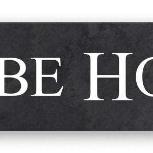 May include: A rectangular sign with the words "GLEBE HOUSE" in white, sans-serif font. The sign has a dark grey, textured background, and a subtle shadow.