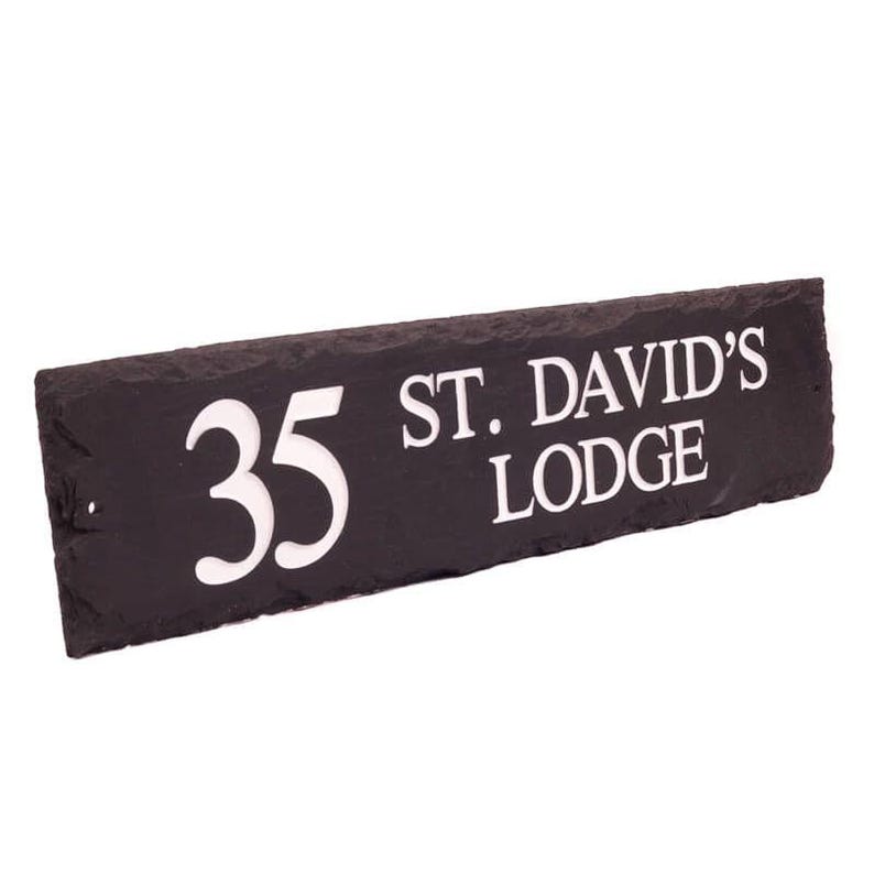 May include: A rectangular black slate house sign with white lettering. The sign reads "35 ST. DAVID'S LODGE". The numbers and text are in a bold, sans-serif font. The slate has a natural, textured surface.