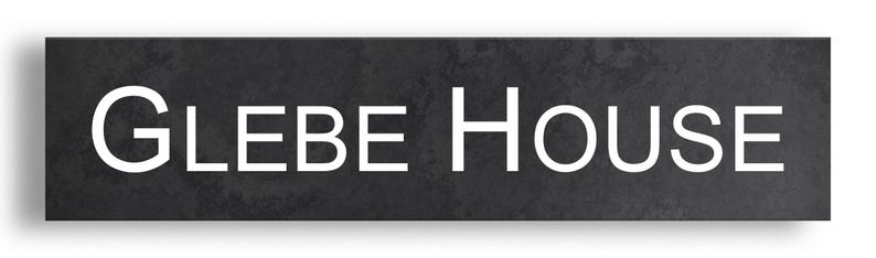 May include: A rectangular, dark grey sign with the words "GLEBE HOUSE" in large, white, sans-serif font. The sign has a textured appearance and a subtle shadow.
