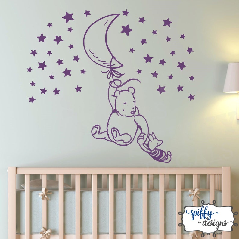 Puede incluir: Pegatina de pared de Winnie de Pooh y Piglet de color morado con un globo en forma de media luna y estrellas. La pegatina est&aacute; en una pared verde claro sobre una cuna blanca.