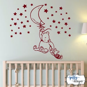 Puede incluir: Pegatina de pared roja de Winnie de Pooh y Piglet con un globo en forma de media luna y estrellas. La pegatina est&aacute; en una pared verde claro sobre una cuna blanca.