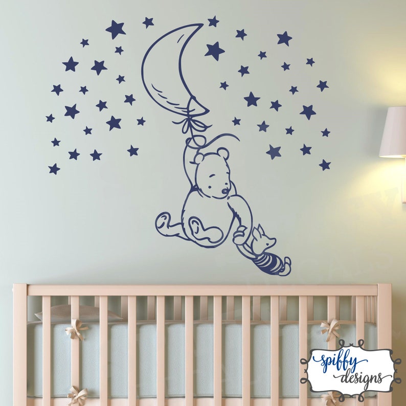 Puede incluir: Una calcoman&iacute;a de pared de Winnie de Pooh y Piglet que muestra a Pooh sujetando un globo en forma de media luna y Piglet sujetando la cola de Pooh. La calcoman&iacute;a es de color azul marino y est&aacute; rodeada de una dispersi&oacute;n de estrellas azul marino.