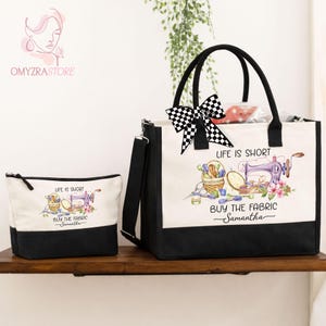 May include: A canvas tote bag and matching cosmetic bag. Both are off-white with black bottoms and handles. The tote bag has a black and white checkered bow. The bags feature a sewing-themed graphic with text that reads "Life is Short, Buy the Fabric".