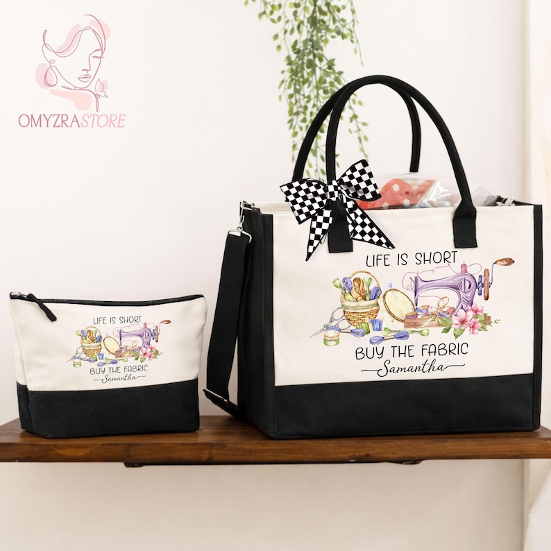 May include: A canvas tote bag and matching cosmetic bag. Both are off-white with black bottoms and handles. The tote bag has a black and white checkered bow. The bags feature a sewing-themed graphic with text that reads "Life is Short, Buy the Fabric".