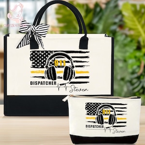 May include: A tote bag and a cosmetic bag featuring a design with an American flag, headphones, and the text "911 DISPATCHER". The bags have black handles and trim. A black and white striped bow adorns the tote bag.