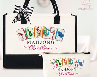 May include: A white tote bag and matching cosmetic bag with black accents. Both bags feature a Mahjong tile design and the name "Christina". The tote has black handles and a striped bow. The cosmetic bag has a zipper closure.