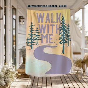 May include: Velveteen plush blanket, 30x40 inches, featuring the text "WALK WITH ME" in purple. The design includes a winding purple path, teal trees, and a watercolor background in yellow, green, and pink.