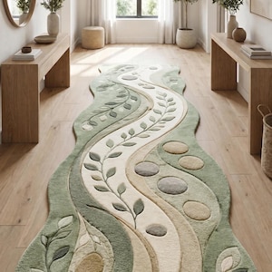 May include: A long, runner rug featuring an organic, wavy shape with a textured surface. The design includes flowing, curved bands in shades of sage green, cream, and beige, accented with raised leaf motifs and circular, stone-like shapes.