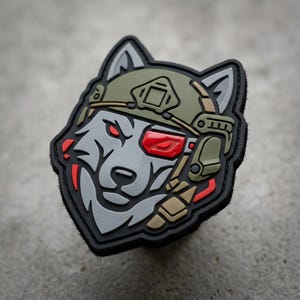 May include: A tactical patch featuring a wolf's head wearing a military helmet and a red-lensed visor. The patch has a black border and is primarily gray, green, and tan in color. The wolf has red eyes.