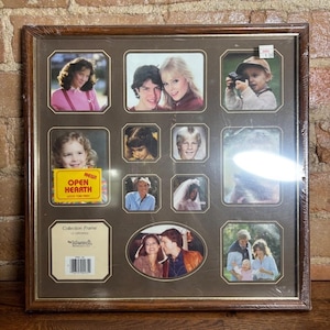 May include: A square brown wood-tone collage picture frame with twelve openings of various shapes and sizes. The frame contains several sample photographs of people and includes a yellow label that reads NEW! OPEN HEARTH WOOD TONE FINISH.