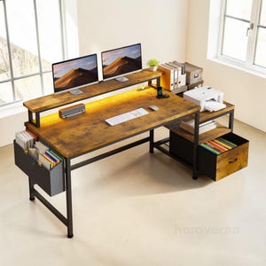 May include: A large, rustic-style computer desk with a monitor shelf, printer shelf, and a drawer. The desk has a brown, distressed wood finish and a black metal frame. Two computer monitors are on the top shelf. A keyboard and mouse are on the desk.