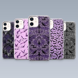 May include: A collection of five phone cases with various bat-themed designs. The cases feature patterns in shades of purple, black, and gray. Designs include bat silhouettes, spiderwebs, and ornate, symmetrical patterns.