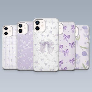 Pode incluir: Cinco capas de telemóvel com desenhos florais e laços em tons de roxo e branco. As capas apresentam diferentes padrões, incluindo pequenas flores, laços e arranjos florais. As capas são feitas de um material transparente.