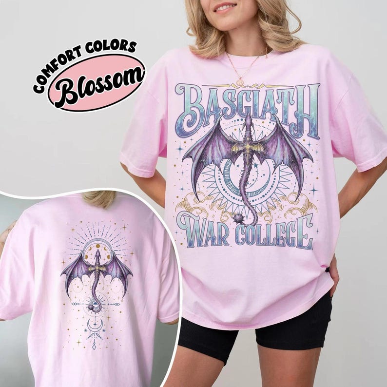 May include: A pale pink t-shirt with a dragon graphic and the words "BASCIATH" and "WAR COLLEGE". The dragon has purple wings and is the central design element. The back of the shirt also features a dragon design.