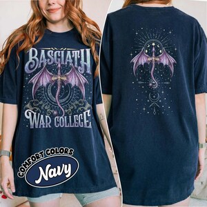 May include: Navy blue t-shirt with a front graphic featuring a purple dragon with outstretched wings, the text "BASCIATH" above, and "WAR COLLEGE" below. The back of the shirt has a matching dragon design. The shirt also has the text "COMFORT COLORS Navy".