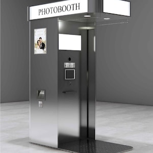 Puede incluir: Un quiosco fotográfico de metal plateado con un letrero iluminado en la parte superior con el texto PHOTOBOOTH. La unidad incluye una interfaz de pantalla táctil central, una lente de cámara, una pantalla pequeña y un retrato enmarcado.