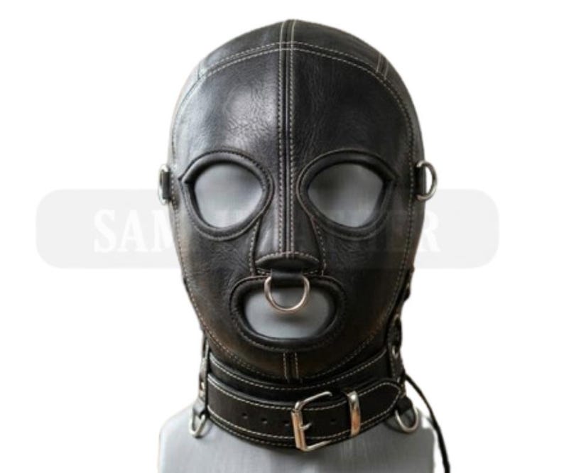 May include: A black leather hood with white stitching, eye and mouth openings, and a metal ring on the mouth. The hood includes a neck collar with a buckle and metal rings. The product is designed for role-playing.