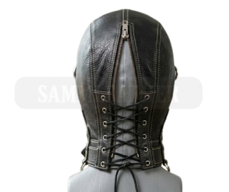 May include: Black leather hood with a zip at the back and a lace-up fastening. The hood features visible stitching and a textured finish. The design includes a neck piece with metal eyelets for the laces.