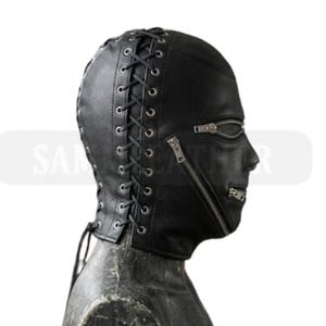 May include: A black leather hood with a full face design. The hood features a lace-up back and two zippers across the face. The hood is designed to cover the entire head and neck.