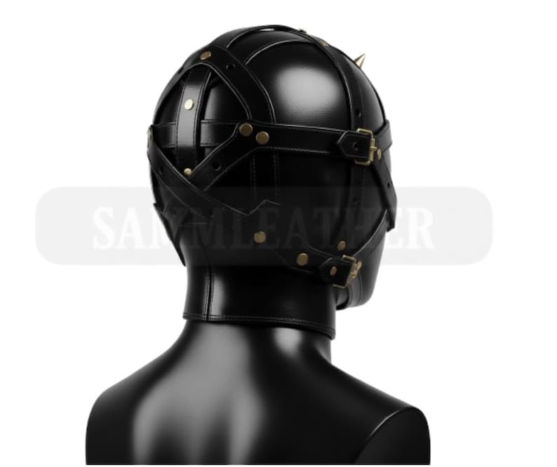 May include: Black leather hood with straps and buckles. The hood features a rounded top with small, gold-colored spikes. The design includes multiple straps that cross over the head and are secured with brass-colored buckles. The product is designed for role-playing.