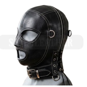 May include: Black leather hood with eye and mouth openings, white stitching, and a zip closure. Features a buckled neck strap and metal rings. The hood is designed for a specific purpose.