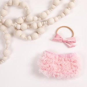 Könnte beinhalten: Rosa geblümte Baby-Blümchen mit einem rosa Samt-Haarband auf weißem Hintergrund.
