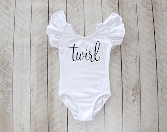 May include: White leotard with short, ruffled sleeves and the word "twirl" printed in black on the front.