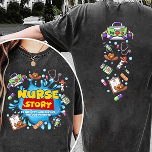 May include: Dark gray t-shirt with a colorful graphic design. The front features the words "NURSE STORY" in yellow and red, with medical-themed illustrations. The back has similar medical-themed graphics, including a medical bag and a stethoscope.