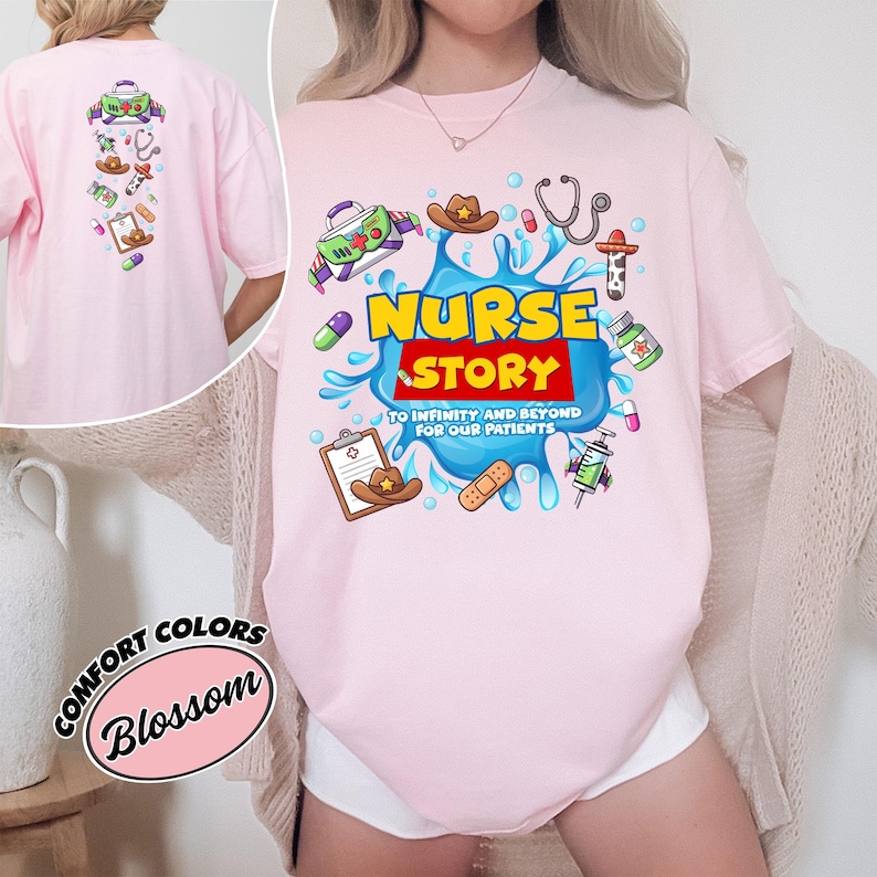 May include: Light pink t-shirt with a colorful graphic that says "Nurse Story" with medical-themed illustrations. The back of the shirt has similar graphics. The shirt is a comfort colors brand.