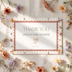 May include: A rectangular thank you card for Amelia's baby shower featuring a scalloped terracotta border, a central illustration of a small duckling, and the text: THANK YOU, AMELIA'S BABY SHOWER, and 10/23/20XX, surrounded by floral accents.
