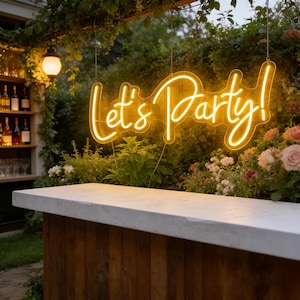 Può includere: Un'insegna al neon gialla brillante con la scritta "Let's Party!" è appesa sopra un bar in legno con un piano di lavoro bianco. Lo sfondo presenta vegetazione lussureggiante, fiori e un piccolo bar con bottiglie, creando un'atmosfera festosa.