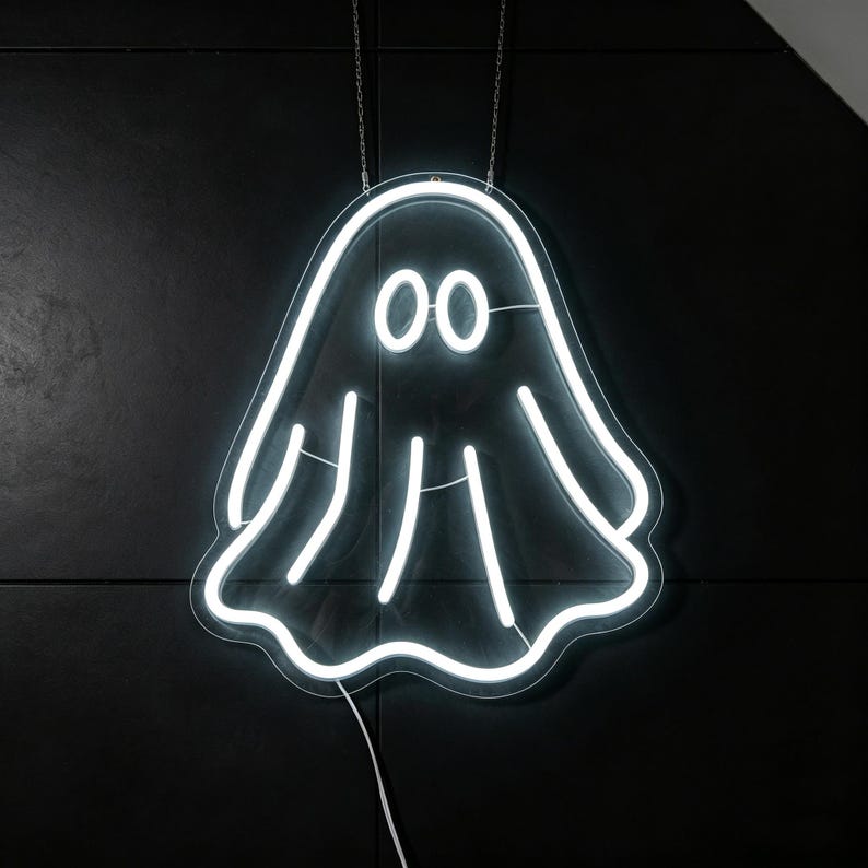 May include: A white neon ghost sign with two round eyes and a wavy bottom edge, hanging against a black background. The sign is suspended by two silver chains, and a white cord extends from the bottom.