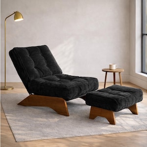 May include: A black corduroy lounge chair and matching ottoman set. The chair has a tufted back and seat, with a wooden base. The ottoman is square and also has a wooden base. A gold floor lamp and small wooden side table are also in the room.