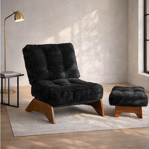 May include: Black corduroy armchair and matching ottoman with wooden legs. The chair has a tufted back and seat. The ottoman is square and also has a tufted top. The chair and ottoman are on a light-colored rug.