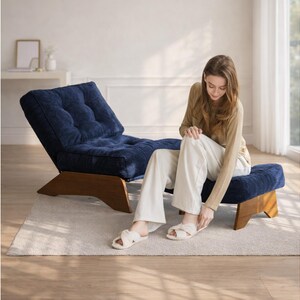 May include: A navy blue corduroy lounge chair and ottoman set with wooden legs. The chair has a tufted back and seat. The ottoman is a matching navy blue corduroy. The set is on a light-colored rug.