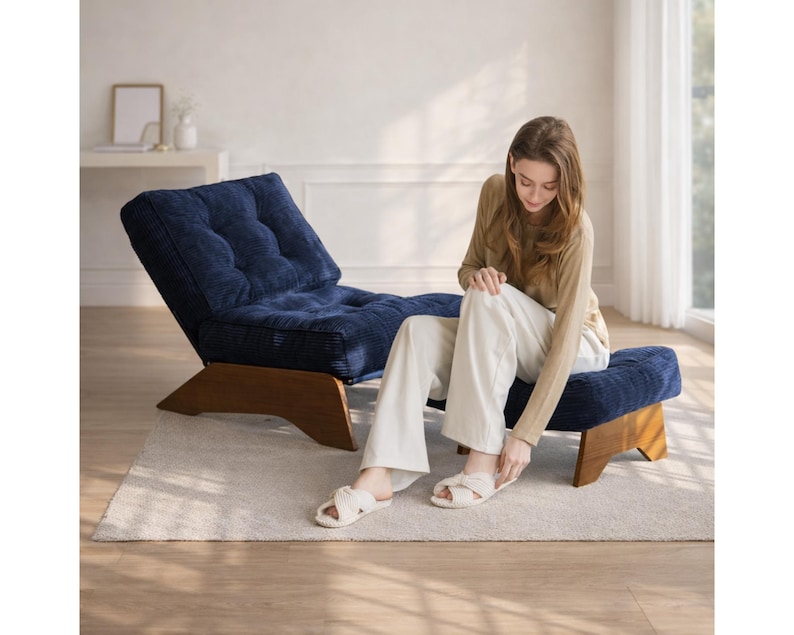 May include: A navy blue corduroy lounge chair and ottoman set with wooden legs. The chair has a tufted back and seat. The ottoman is a matching navy blue corduroy. The set is on a light-colored rug.
