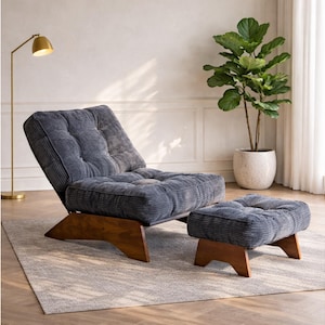 May include: A modern, corduroy upholstered chair and ottoman set in a muted blue-gray hue. The chair features a reclining back and sits on a wooden base. The ottoman mirrors the chair's design. A gold floor lamp and potted plant are in the background.