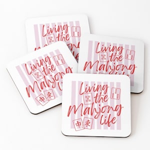 May include: Four square coasters with a white background and pink vertical stripes. Each coaster has the phrase "Living the Mahjong Life" in red script, along with Mahjong tile graphics.