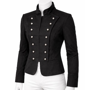 Puede incluir: Chaqueta negra con cuello alto y diseño cruzado. La chaqueta presenta botones plateados y mangas largas. El corte entallado y la silueta estructurada crean un look clásico y elegante. La chaqueta se muestra en un maniquí.