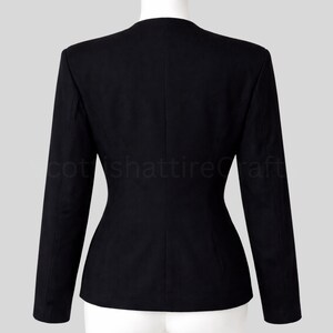 Puede incluir: Un blazer negro con un corte entallado, con un dise&ntilde;o cl&aacute;sico sin cuello y mangas largas. La chaqueta tiene una cintura entallada y una textura lisa y s&oacute;lida. Vista trasera del blazer en un maniqu&iacute;.
