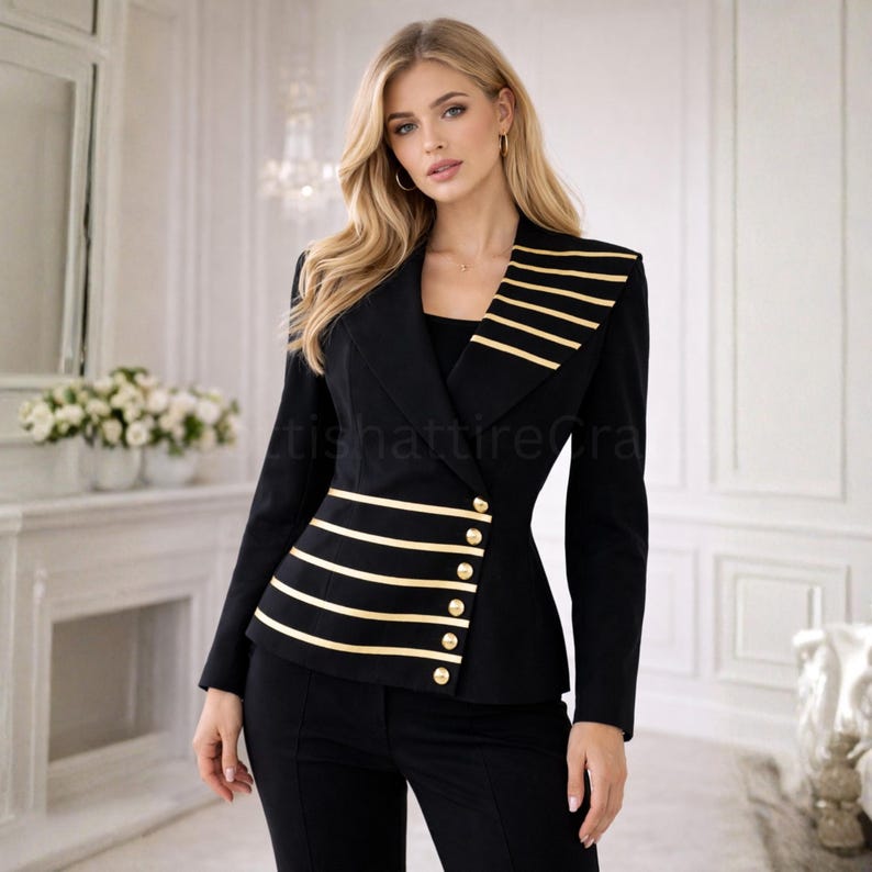 Puede incluir: Una blazer negra con rayas horizontales doradas y botones dorados. La blazer tiene un corte entallado y se combina con pantalones negros. La modelo lleva pendientes de aro dorados.