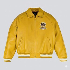 May include: Mustard yellow leather jacket with a zip-up front, collar, and two front pockets. The jacket features a patch on the chest with the text "AVIREX 1975". The cuffs and waist have white and yellow striped detailing.
