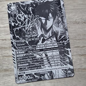 May include: A black and white trading card featuring an illustration of the character Sung Jinwoo. The card displays the text On to the Next Target, Sung Jinwoo, and includes game mechanics, a 5000 BP value, and a 12 Action cost icon.