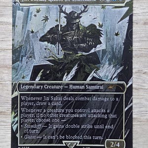May include: A Magic: The Gathering trading card featuring Jin Sakai, Ghost of Tsushima. The artwork depicts a samurai in dark armor with a horned helmet, surrounded by falling leaves. The card text includes abilities, power and toughness 2/4.