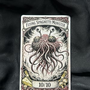 May include: A rectangular card featuring the Flying Spaghetti Monster, with two large eyeballs and a mass of spaghetti-like appendages. The card has a detailed, vintage-style illustration with the text "Flying Spaghetti Monster" at the top and "10/10" at the bottom.