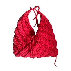 Könnte beinhalten: Eine leuchtend rote, handgehäkelte Tasche mit einem einzigartigen, strukturierten Design. Die Tasche hat einen Kordelzugverschluss und eine unverwechselbare, offene Form. Die leuchtend rote Farbe und das grobe Gestrick schaffen ein auffälliges Accessoire.