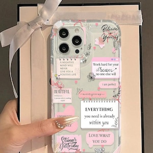 May include: Transparent phone case with a pink and white design. The case has motivational quotes and floral details. Text includes phrases such as "Believe in Yourself" and "Everything you need is already within you."