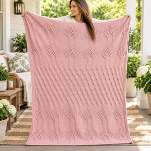 May include: A large, rectangular, dusty pink knitted throw blanket featuring a repeating textured pattern of vertical cable-knit tree motifs and a central band of raised bobble stitches, finished with a simple knit border along all four edges.