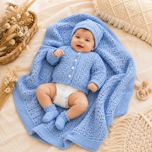 Peut inclure: Un ensemble tricoté bleu clair pour bébé comprenant un gilet à manches longues boutonné, un bonnet assorti et une paire de chaussons. L'ensemble présente un motif ajouré complexe et est présenté sur une couverture tricotée bleu clair.