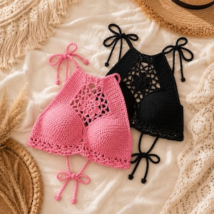 Puede incluir: Dos tops halter de ganchillo, uno en rosa brillante y otro en negro, con un patrón floral central, copas sólidas y tiras ajustables para atar en el cuello y la espalda. Los tops están confeccionados con intrincadas puntadas de hilo.